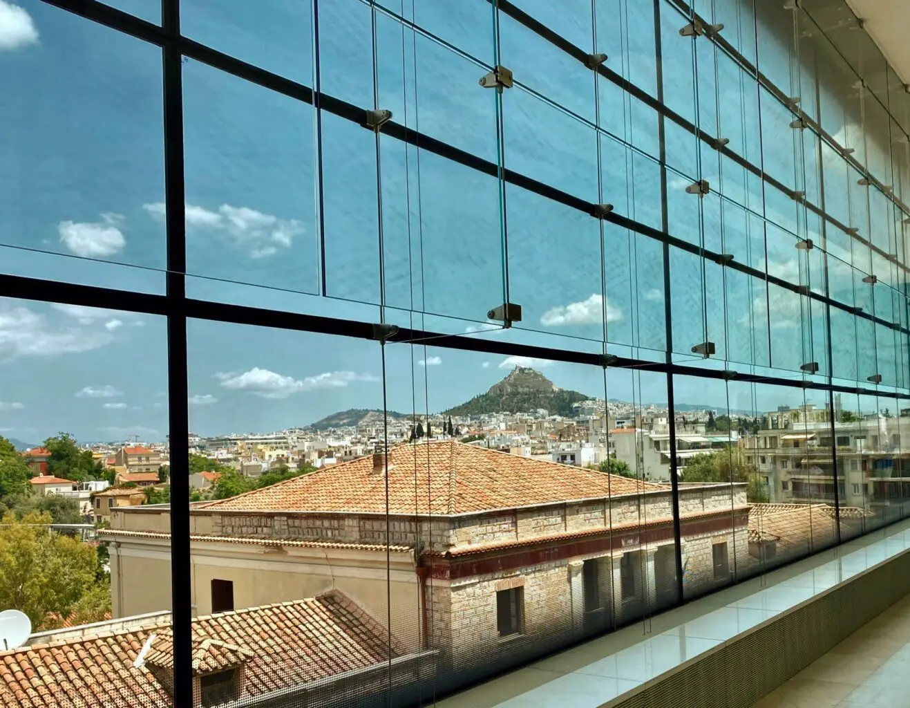 View of Athens through a glass structure illustrating systems thinking in contact center operations.