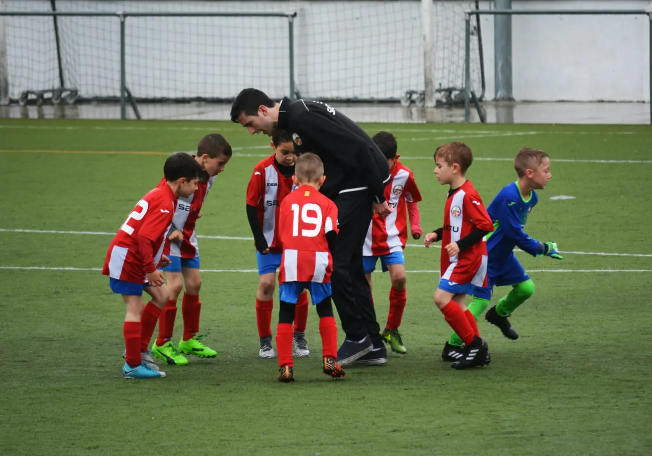 Team coach guiding young players during a coaching session representing Quality Assurance coaching and performance improvement.